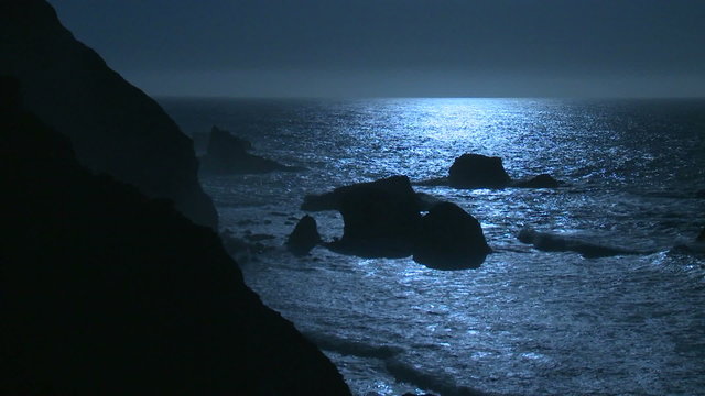 Surf rolls into the Big Sur Coastline of California under a full moon effect.