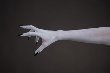 Scary pale skin hand with black nails