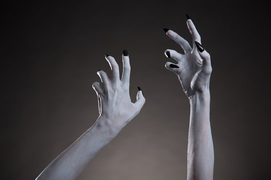 Spooky Halloween white hands with black nails stretching up