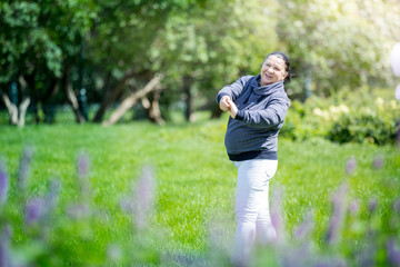 Naklejka na ściany i meble Senior woman doing exercises in green beautiful park. Healthy lifestyle