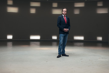 Portrait of young entrepreneur with red tie standing in empty ha