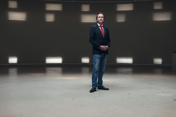 Portrait of young entrepreneur with red tie standing in empty ha