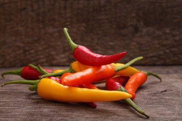hot red, yellow, orange peppers on the old wooden background