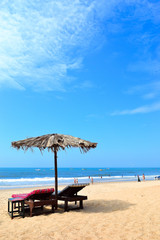 Two sunbeds with umbrella for relaxation on the beach Goa, India
