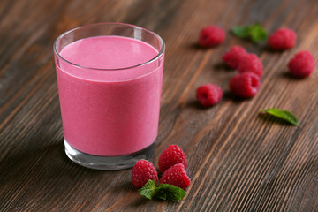 Glass of raspberry milk shake with berries on wooden background