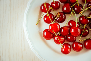 Sweet cherries on plate, on light background