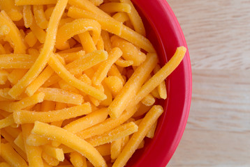 Shredded sharp cheddar cheese in red bowl