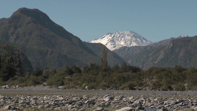 Slow move out of a dry river bed and snow capped peak in the Andes above Talca, Chile.