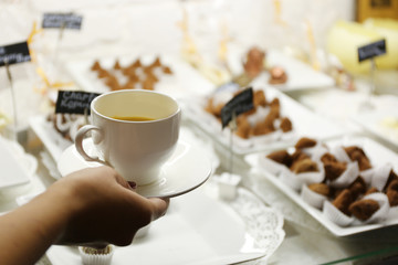 Female hand holding cup of coffee on table background