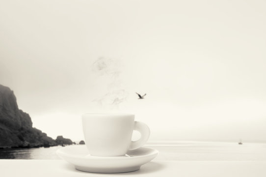 black and white photo of a cup of coffee on a background seascape