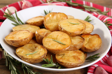 Delicious baked potato with rosemary in bowl on table close up