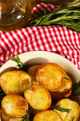 Delicious baked potato with rosemary in bowl on table close up