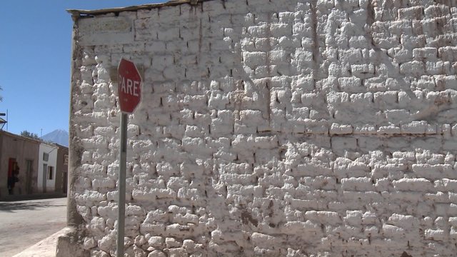 Pan across a whitewashed brick wall and the volcano Lincancabur, San Pedro de Atacama, Chile.