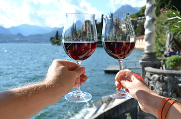 Two wineglasses in the hands. Varenna town at the lake Como, Italy