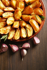 Baked potato wedges on wooden table, top view