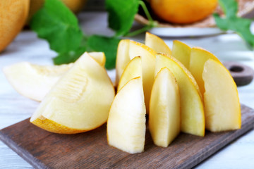 Slices of ripe melons with green leaves on table close up