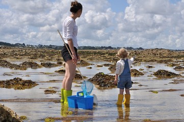Une mère et sa fille cherchent de petits crabes à marrée basse