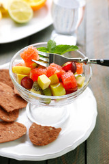 Fruit salad in glass bowl, on wooden background
