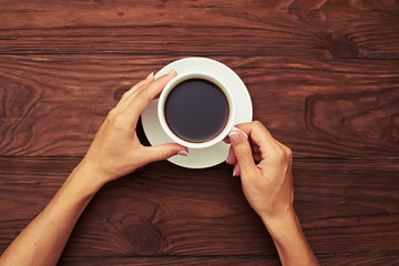 womans hands holding cup of coffee