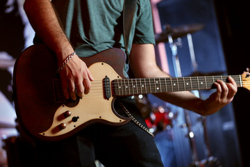 Young man playing on electric guitar close up