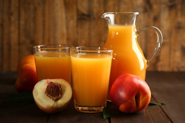 Peach juice and ripe peaches on wooden background