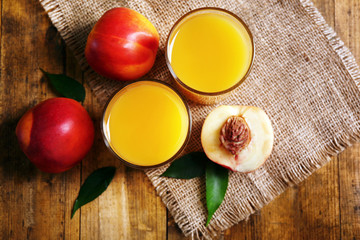 Ripe peaches and glass of juice on wooden background