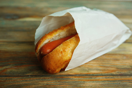 Fresh Hot Dog In Paper Bag On Wooden Background