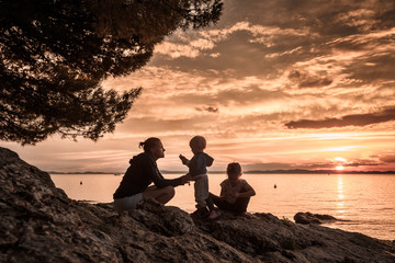 Mother with children sitting on beach, talking and playing