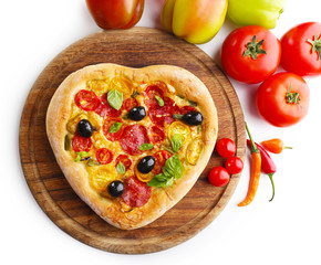 Heart shaped pizza and fresh vegetables on cutting board isolated on white