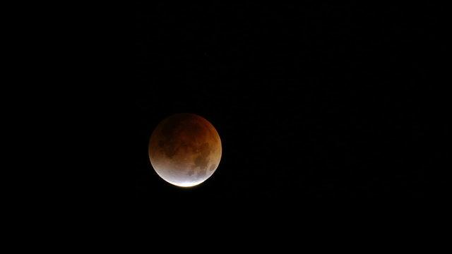 Time lapse of a lunar eclipse with moon moving across frame.