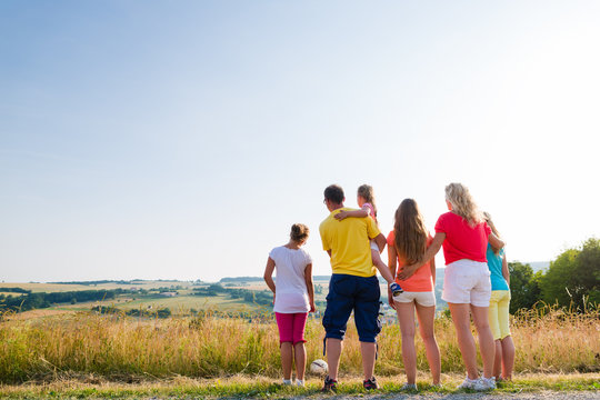 Familie bei Spaziergang betrachtet die Landschaft der Heimat an einem Sommerabend