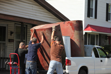 Men lifting heavy metal tank onto pickup truck