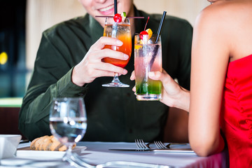 Asian couple drinking cocktails in fancy bar