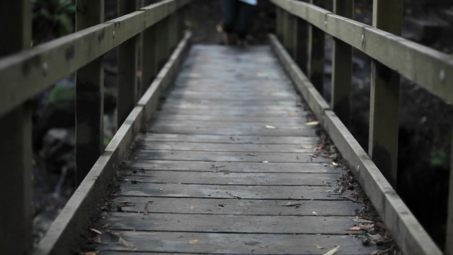 Person wearing socks (but no shoes) runs over wooden bridge.