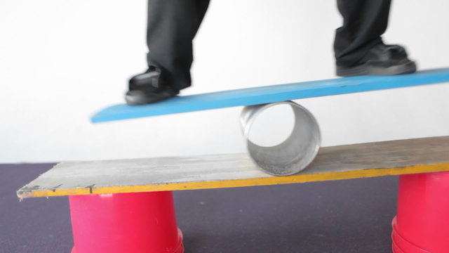 A man balances on a board and a tube.