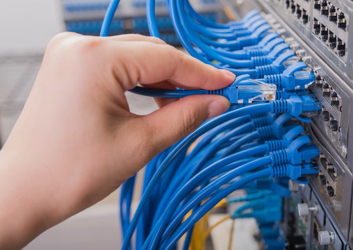man connecting network cable to switch