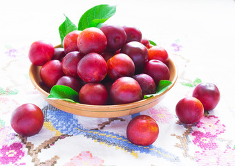 Juicy ripe plums on a white embroidered table cloth