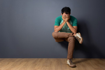 Naklejka premium Young man sitting and covering his face