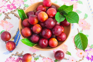 Juicy ripe plums on a white embroidered table cloth