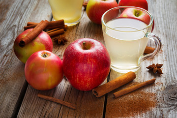 Apples, cider and cinnamon on old wooden table