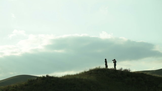the man photographs the girl on a hill in the wind