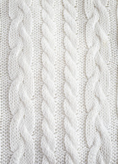 Fototapeta na wymiar Knitted white texture with a pattern of braids