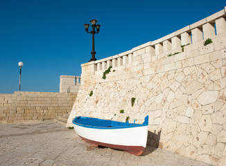 Fototapeta na wymiar Old boat resting on harbor wall