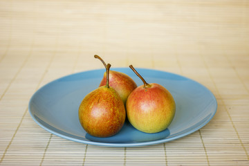 three ripe pears on a blue plate