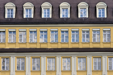 Facade with rows of windows.Mansard roof and yellow facade in typical german architecture style building. Munich,Bavaria,Germany.