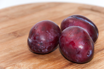 Close view of fresh plums on the wooden board