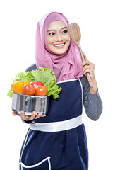 young woman carrying a pan full of vegetables and wooden spatula