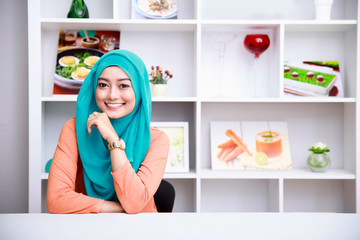 beautiful woman wearing hijab at living room with decorated back