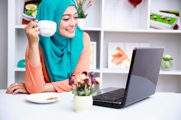 young muslim woman enjoying morning day with a cup of tea and mo