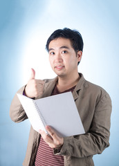 Asian businessman holding pen and writing notebook, on blue back